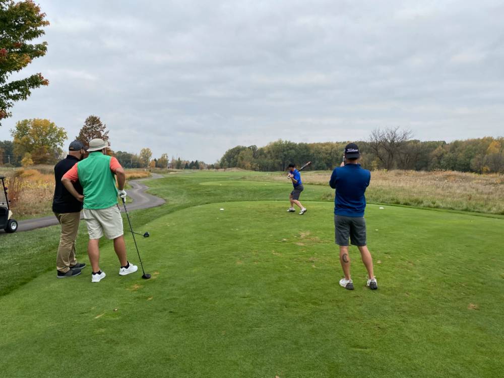 Four alumni hitting baseball on golf course